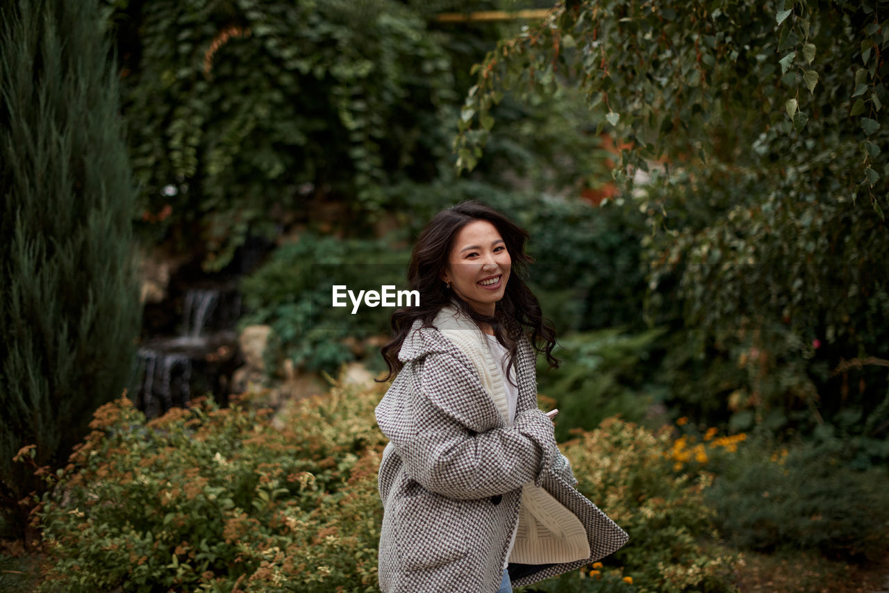 portrait of young woman standing against plants