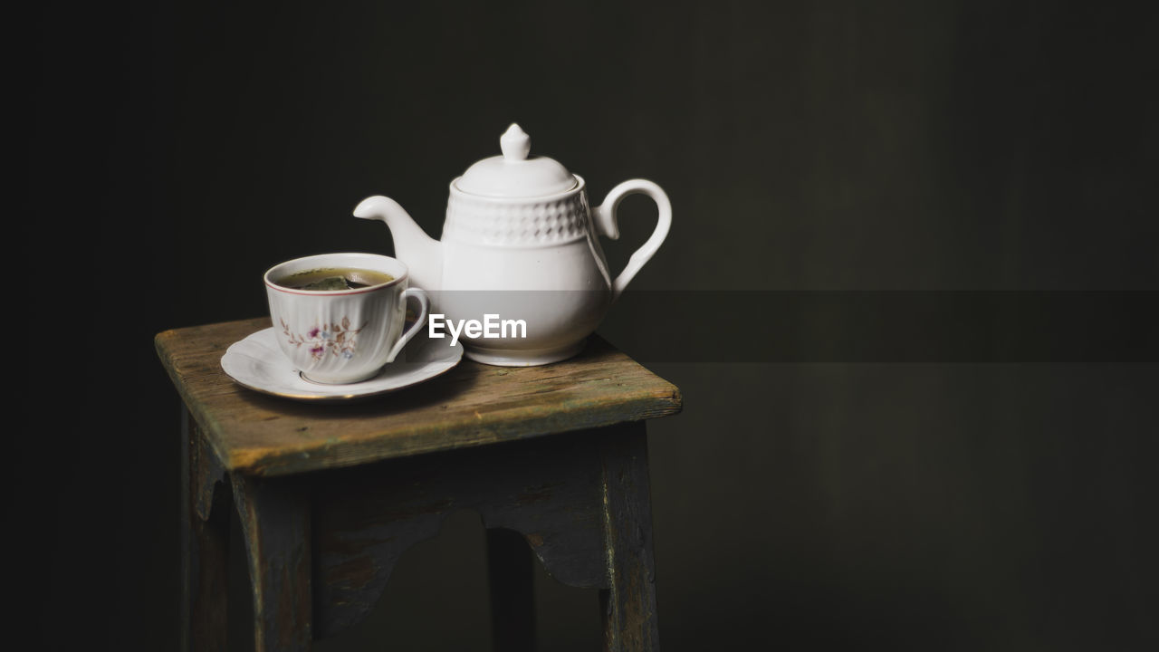 teapot, cup, mug, drink, tea, hot drink, food and drink, black background, studio shot, tea cup, indoors, still life, refreshment, table, still life photography, ceramic, no people, crockery, porcelain, kettle, wood, afternoon tea, copy space, food, simplicity, tableware, white, kitchen utensil, cut out, milk jug, wellbeing, freshness