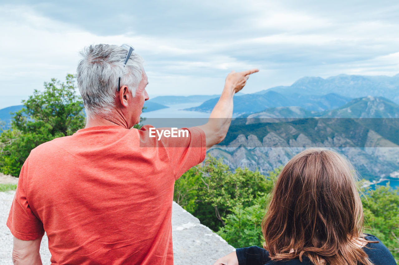 Rear view of woman looking at mountains against sky