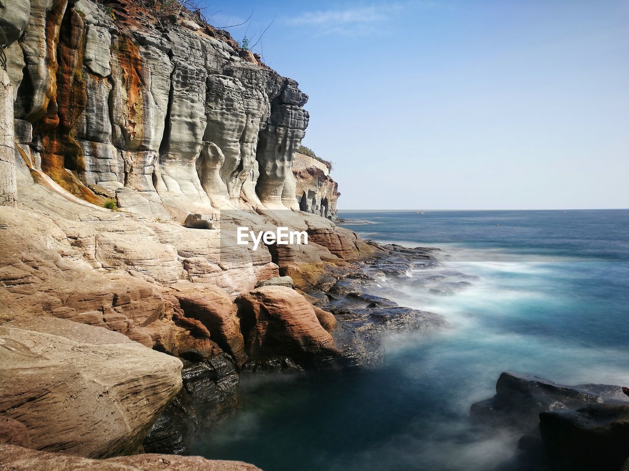 Rock formations by sea against clear sky