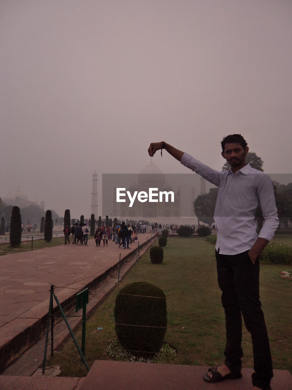 YOUNG MAN WITH ARMS OUTSTRETCHED STANDING AGAINST SKY