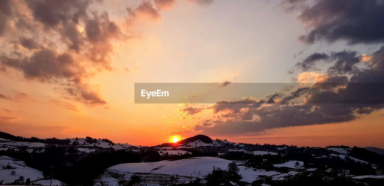 Scenic view of snowcapped mountains against sky during sunset