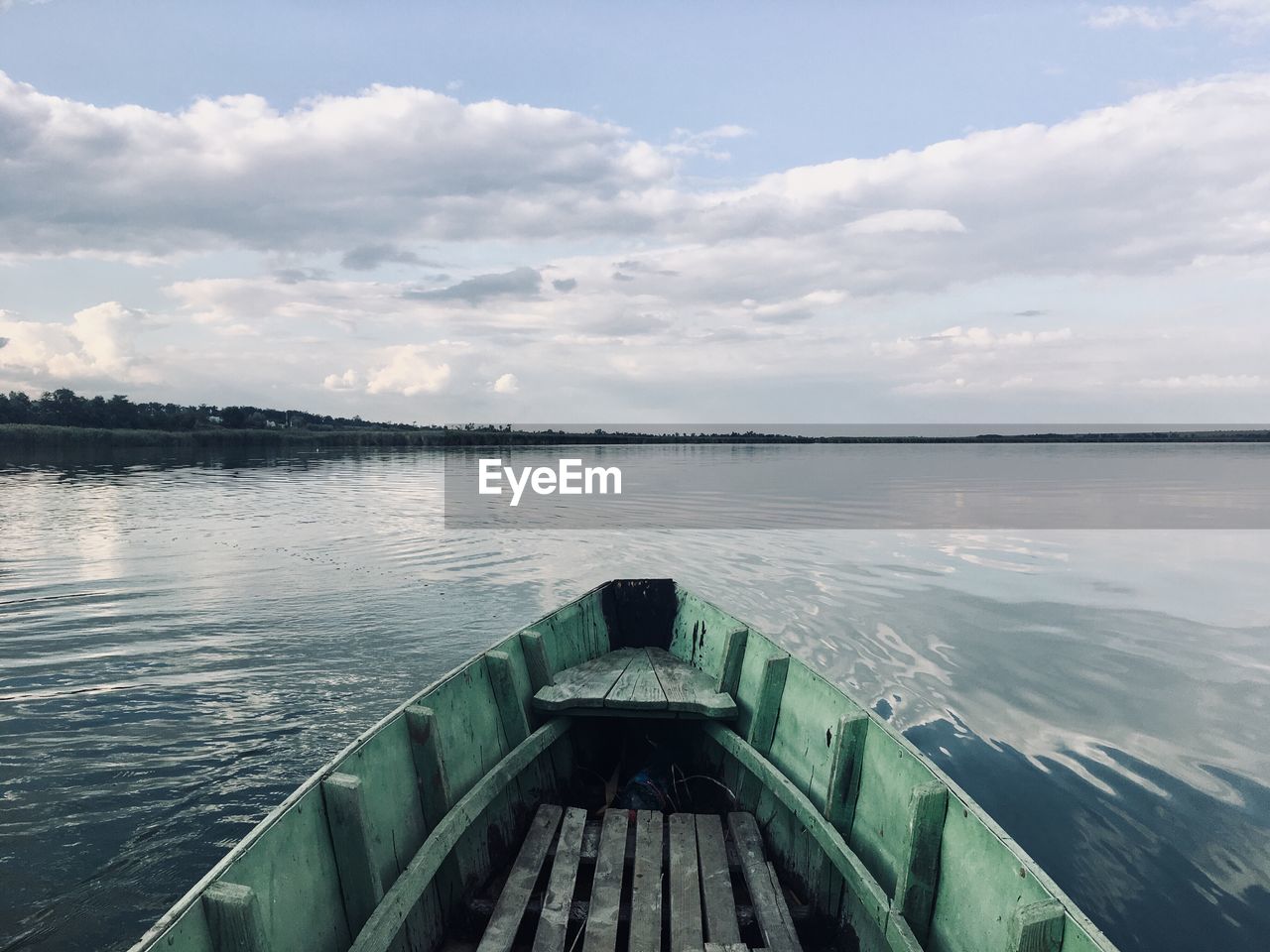 Cropped image of boat in lake against cloudy sky