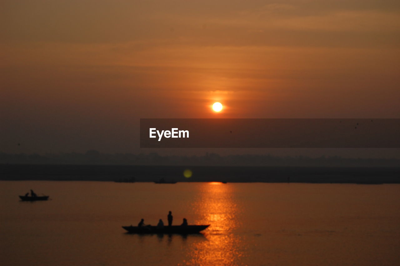 SILHOUETTE BOATS IN SEA AGAINST SKY AT SUNSET