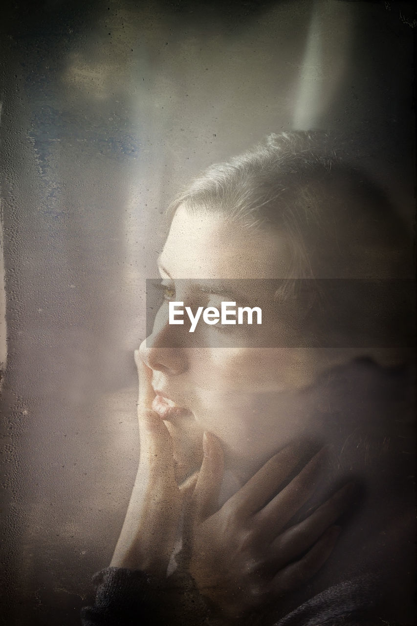 PORTRAIT OF YOUNG WOMAN LOOKING AWAY AGAINST BLURRED BACKGROUND