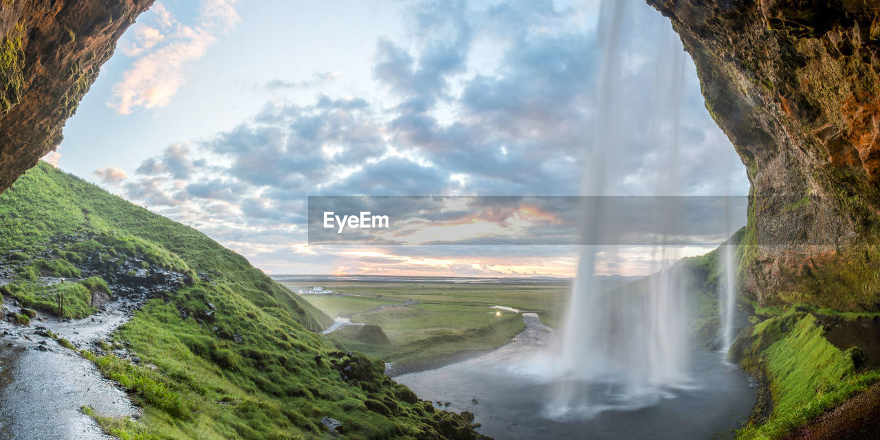 Scenic view of waterfall against cloudy sky