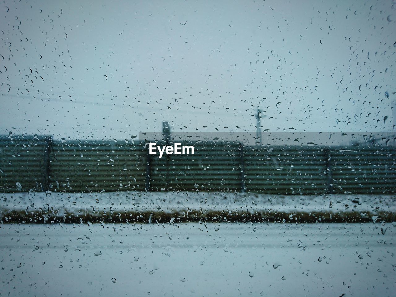 FULL FRAME SHOT OF WET GLASS WINDOW AGAINST SKY