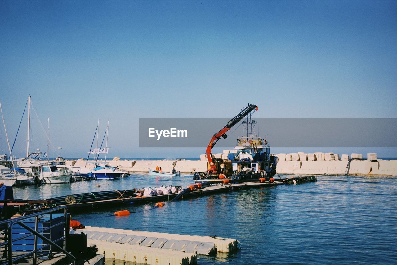 Fishing boats at harbor  a platform with equipment for digging at the bottom of the port a crane 