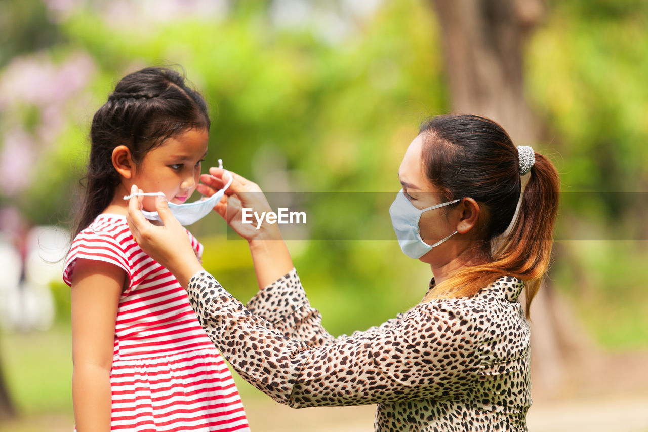 Mother wearing mask to daughter outdoors