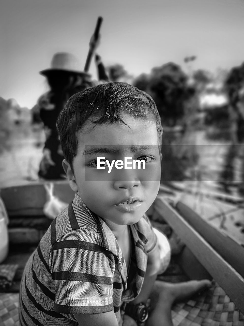 Side view portrait of boy sitting on rowboat in river