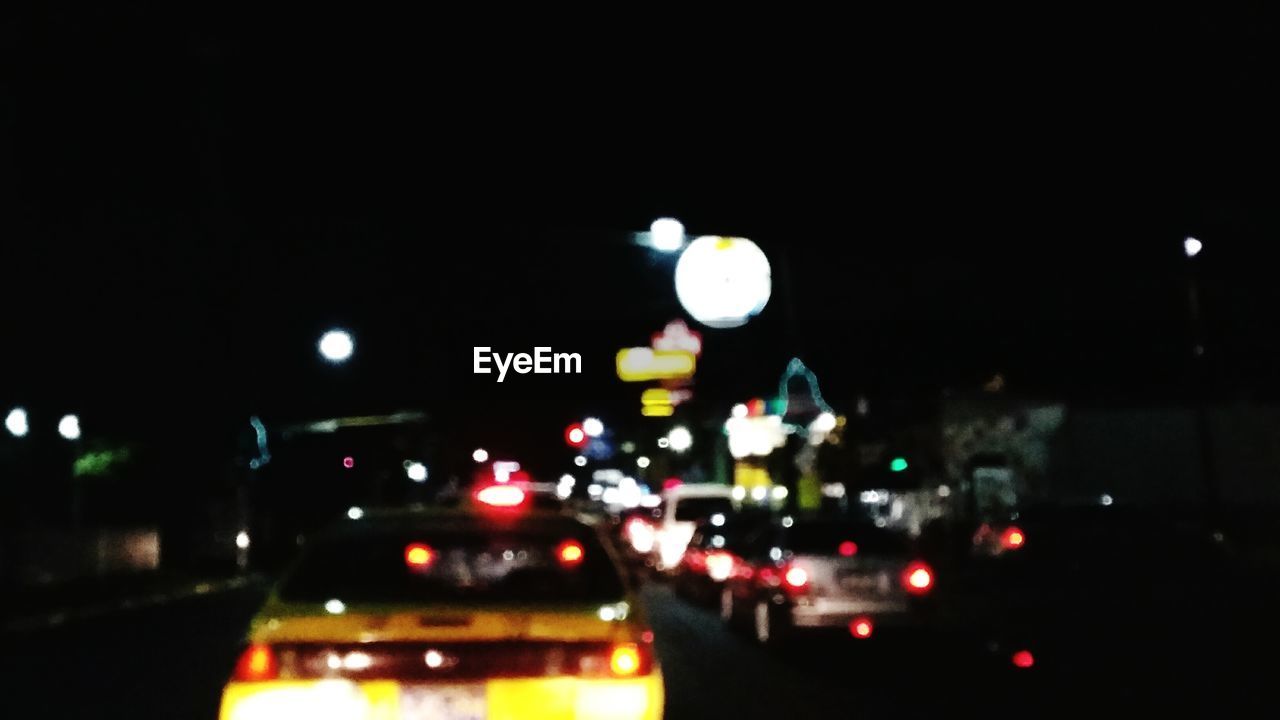 CLOSE-UP OF ILLUMINATED CAR ON ROAD IN CITY