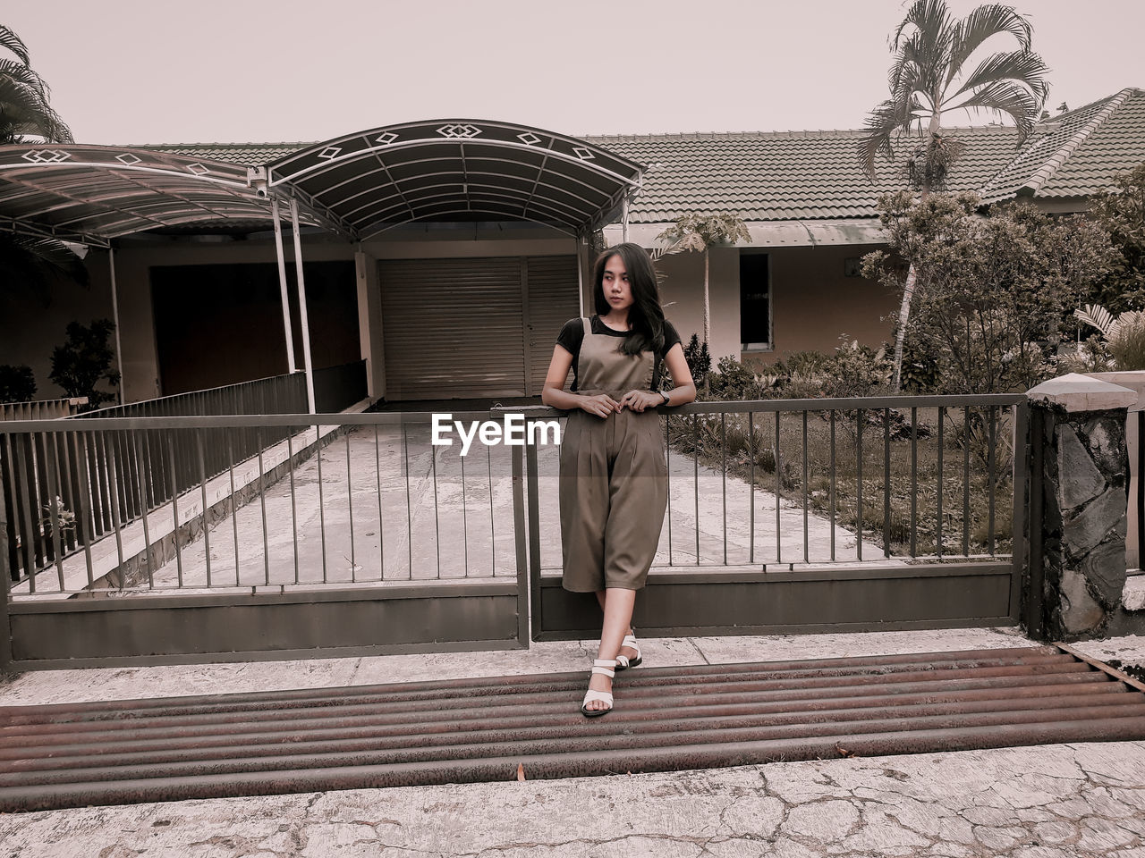 FULL LENGTH OF WOMAN STANDING ON RAILING AGAINST BUILDINGS