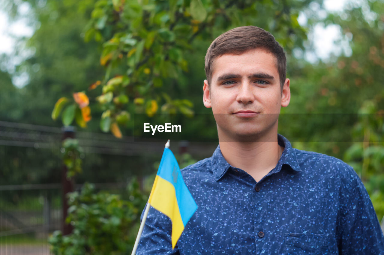 Ukrainian man. young smiling man holding ukrainian flag. no war. support for ukraine. patriotic