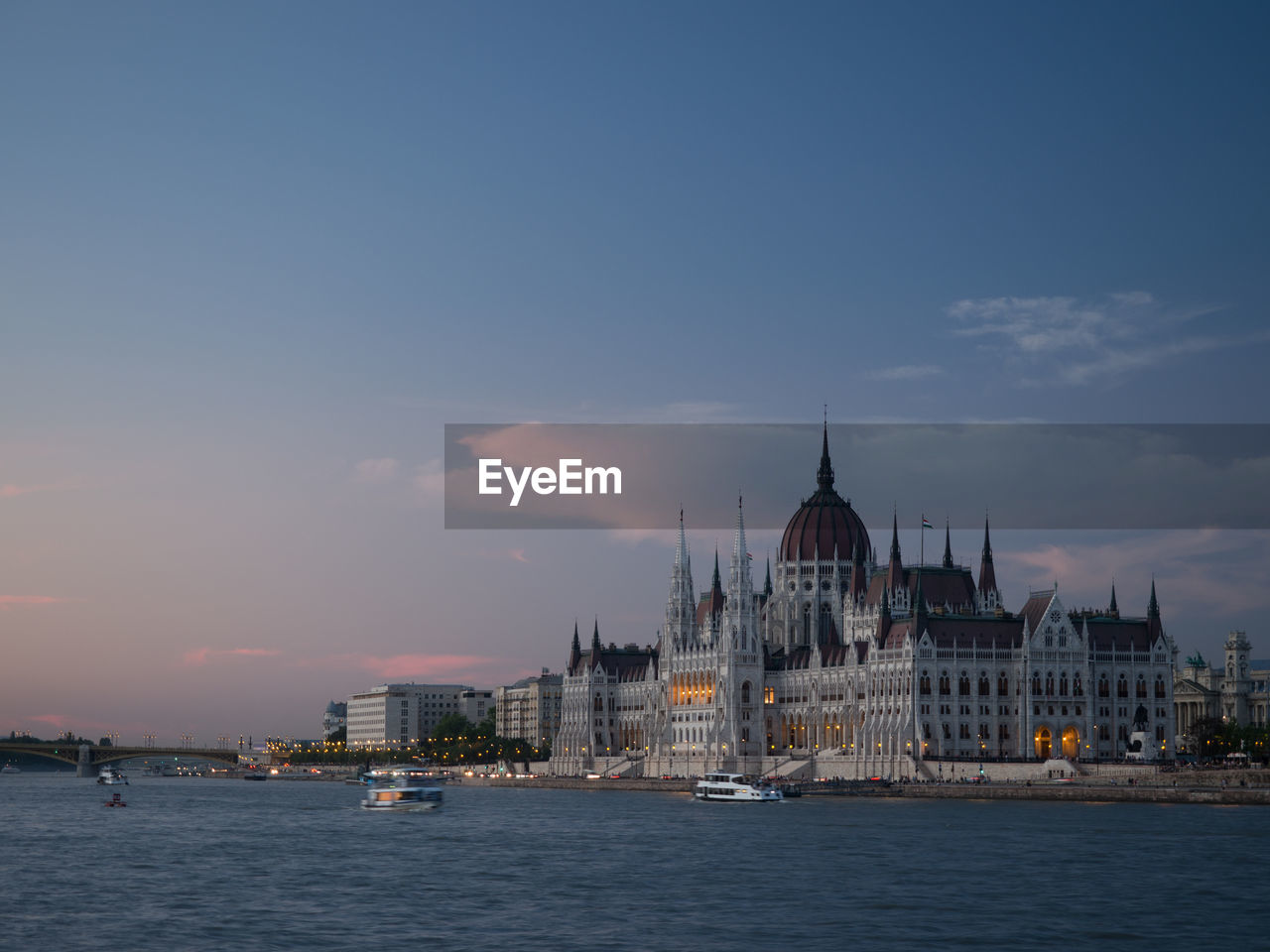 View of buildings by river against sky in city