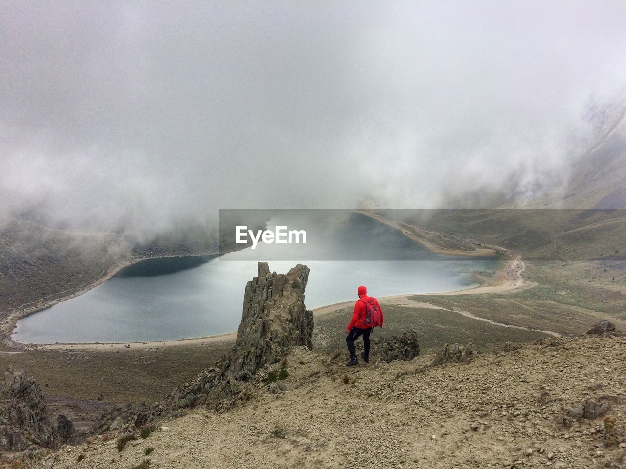 REAR VIEW OF PERSON STANDING ON MOUNTAIN