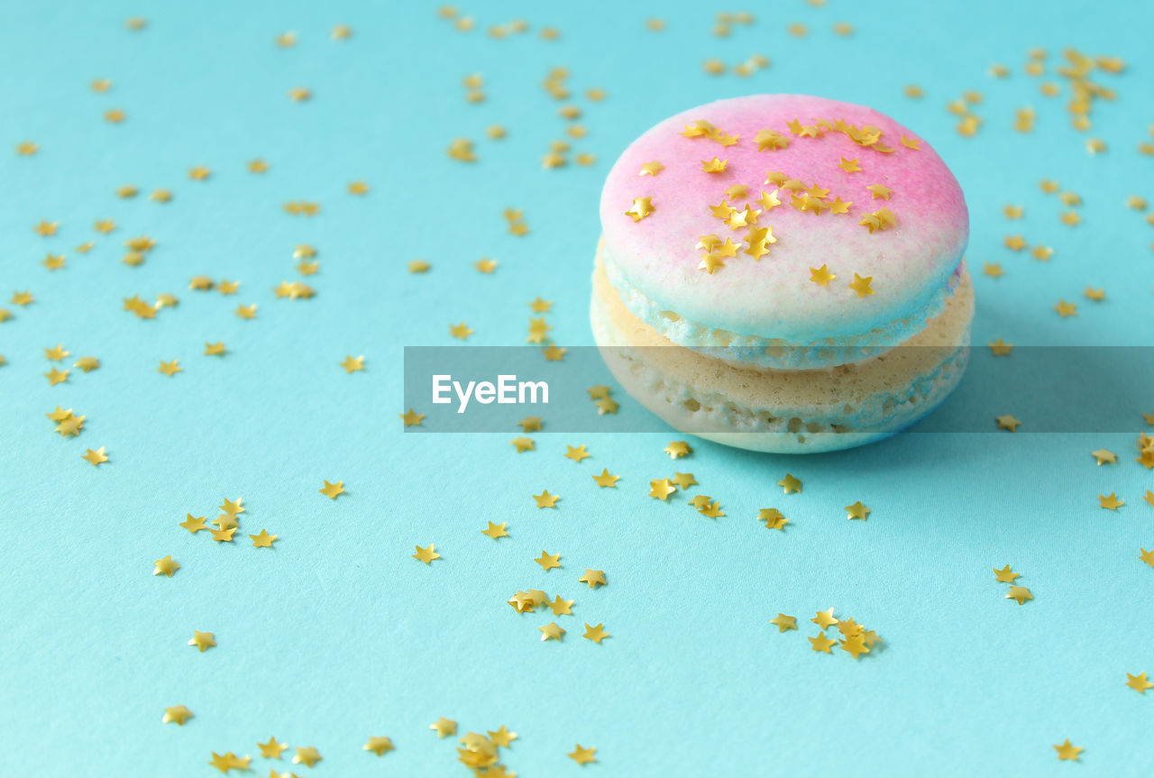 Close-up of macaroon and star shaped sequins on blue background