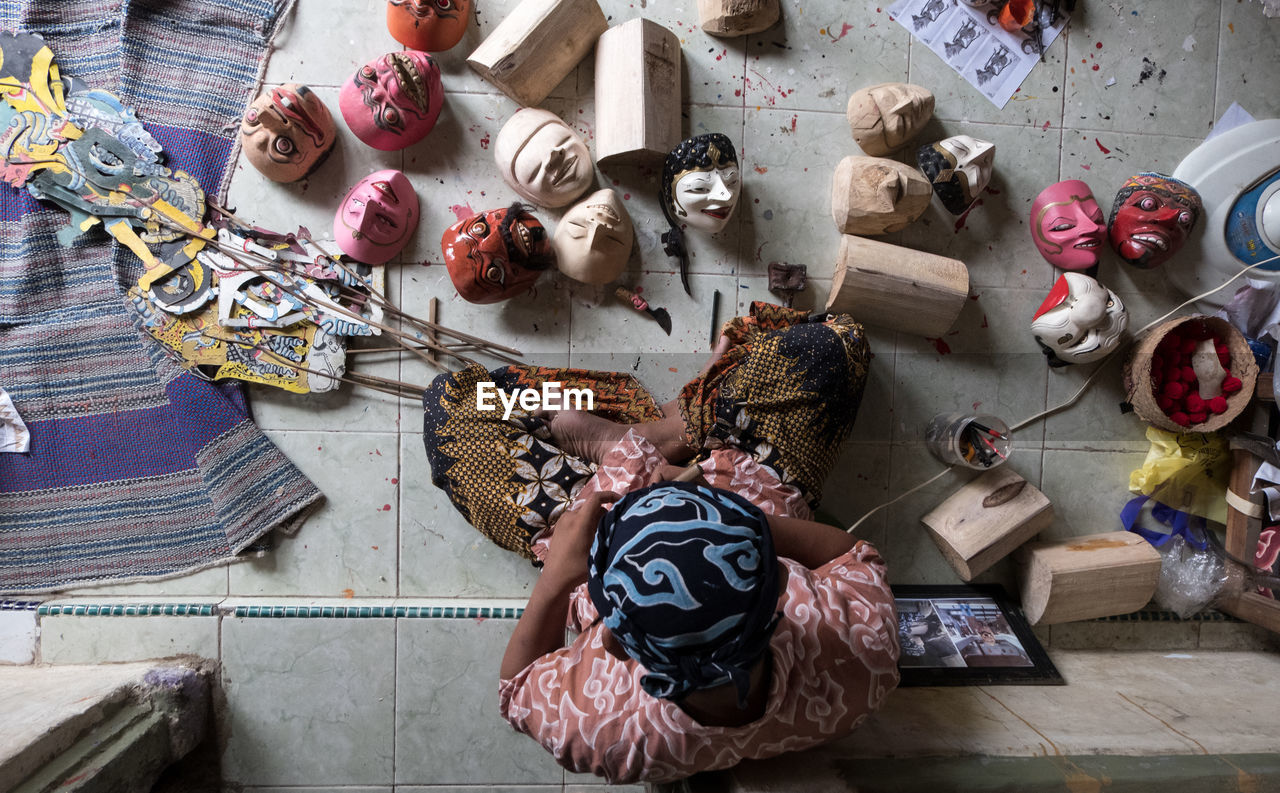 High angle view of man making sculptures while sitting on floor