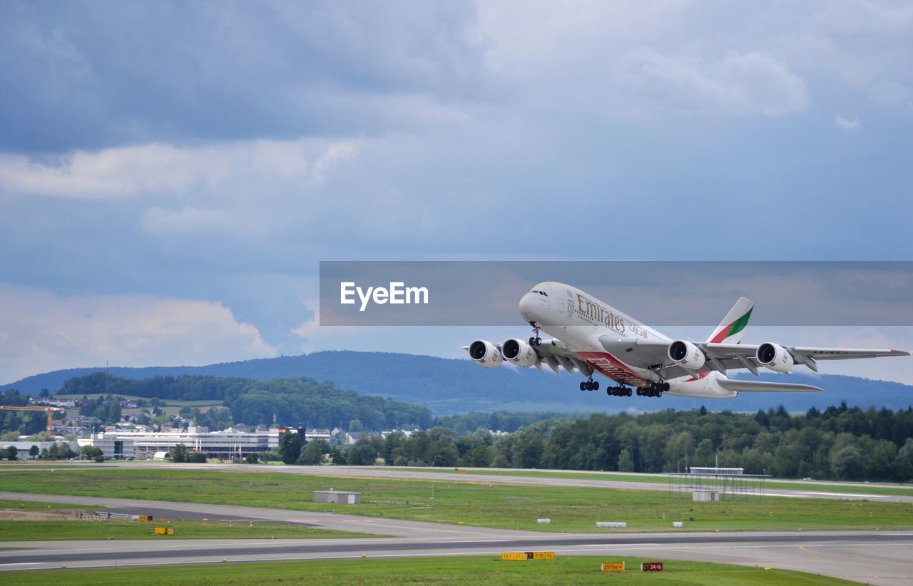 AIRPLANE FLYING ABOVE RUNWAY