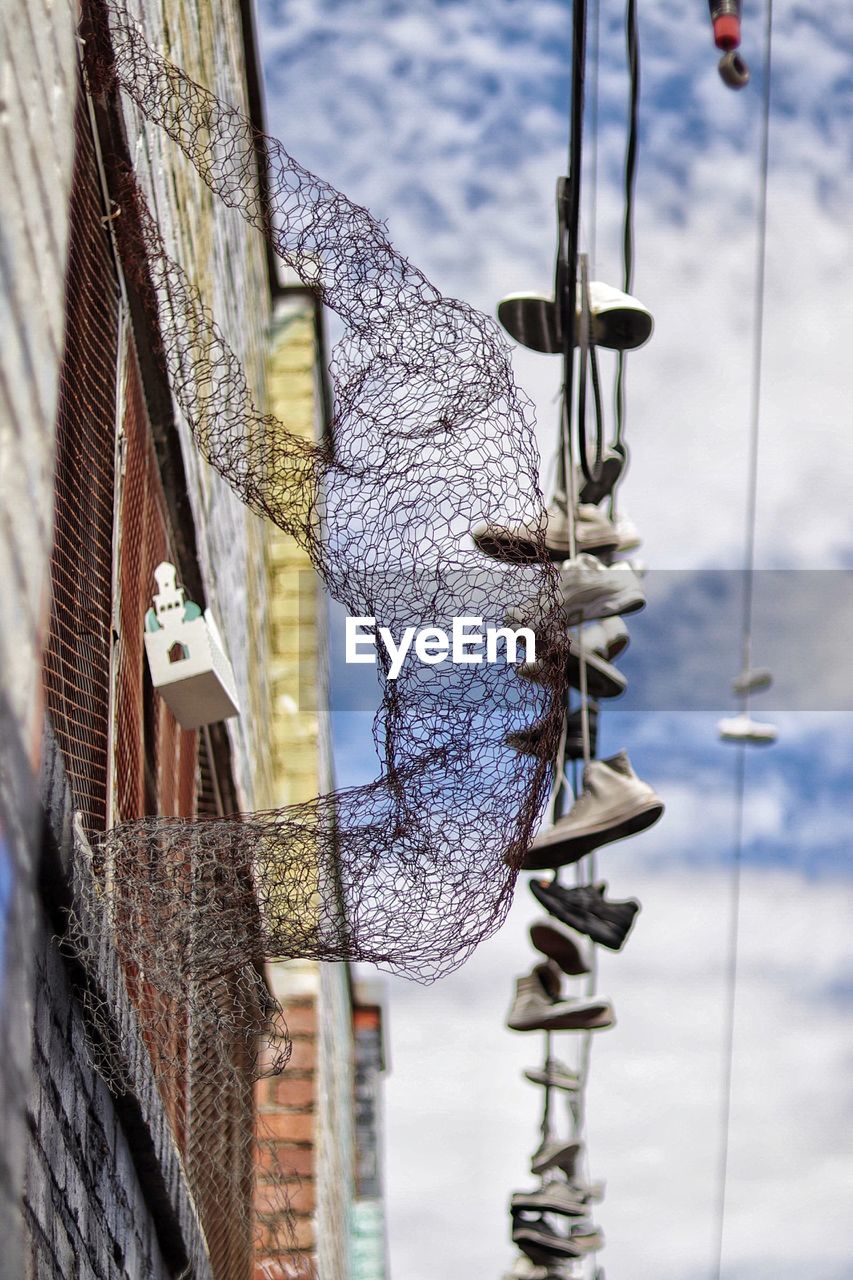 LOW ANGLE VIEW OF ROPES HANGING ON ROPE POLE AGAINST BUILDING