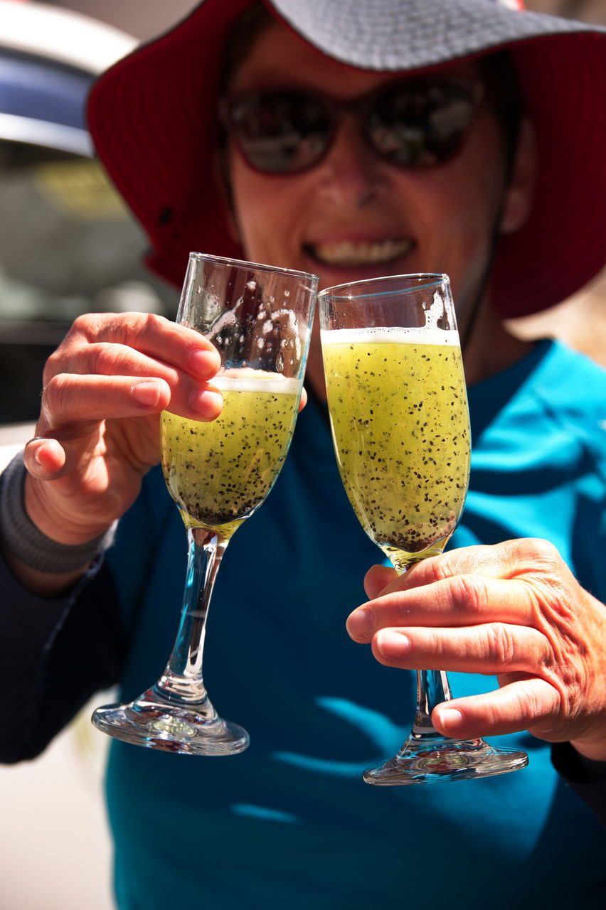 Senior woman holding two glasses of cactus juice in peru