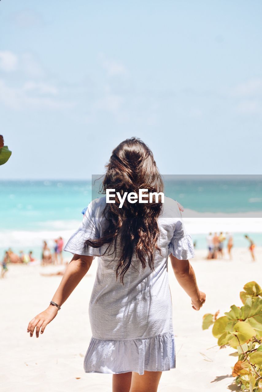 Rear view of woman  on beach against sky