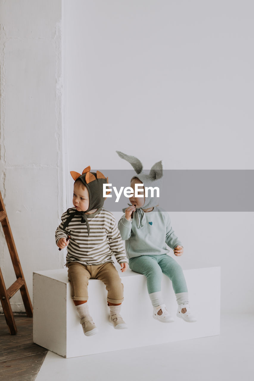 Toddler twins in funny hats with ears sitting and smiling