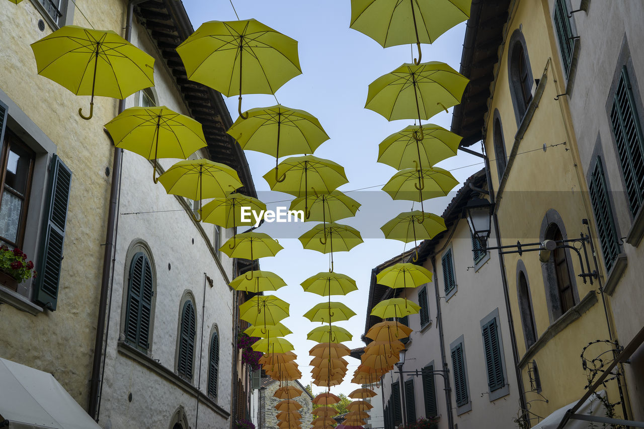 LOW ANGLE VIEW OF DECORATED HANGING BY BUILDING AGAINST SKY