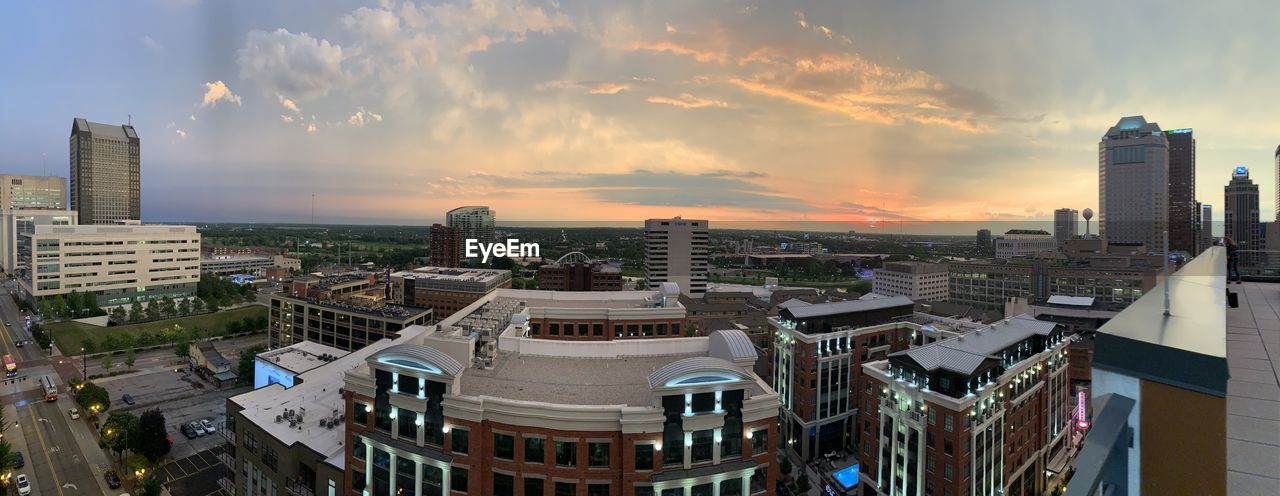 HIGH ANGLE VIEW OF BUILDINGS AGAINST SKY AT SUNSET