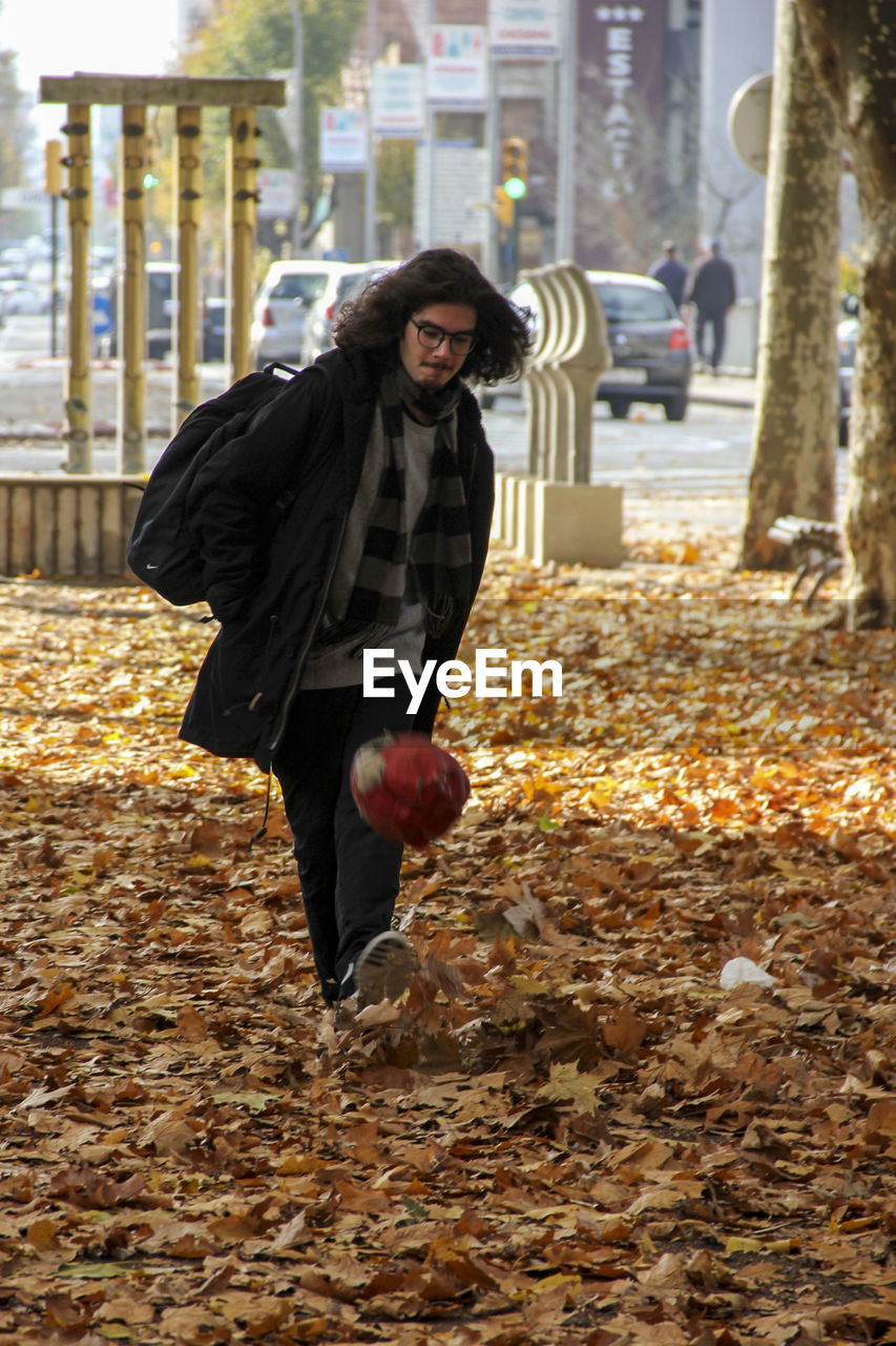 Young man playing with ball on field during autumn