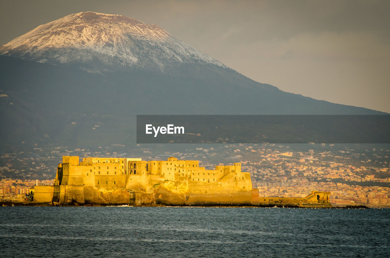 Scenic view of sea by mountain against sky