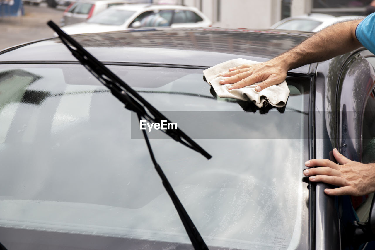 Satisfied mature man polishing his car with microfiber cloth. close-up