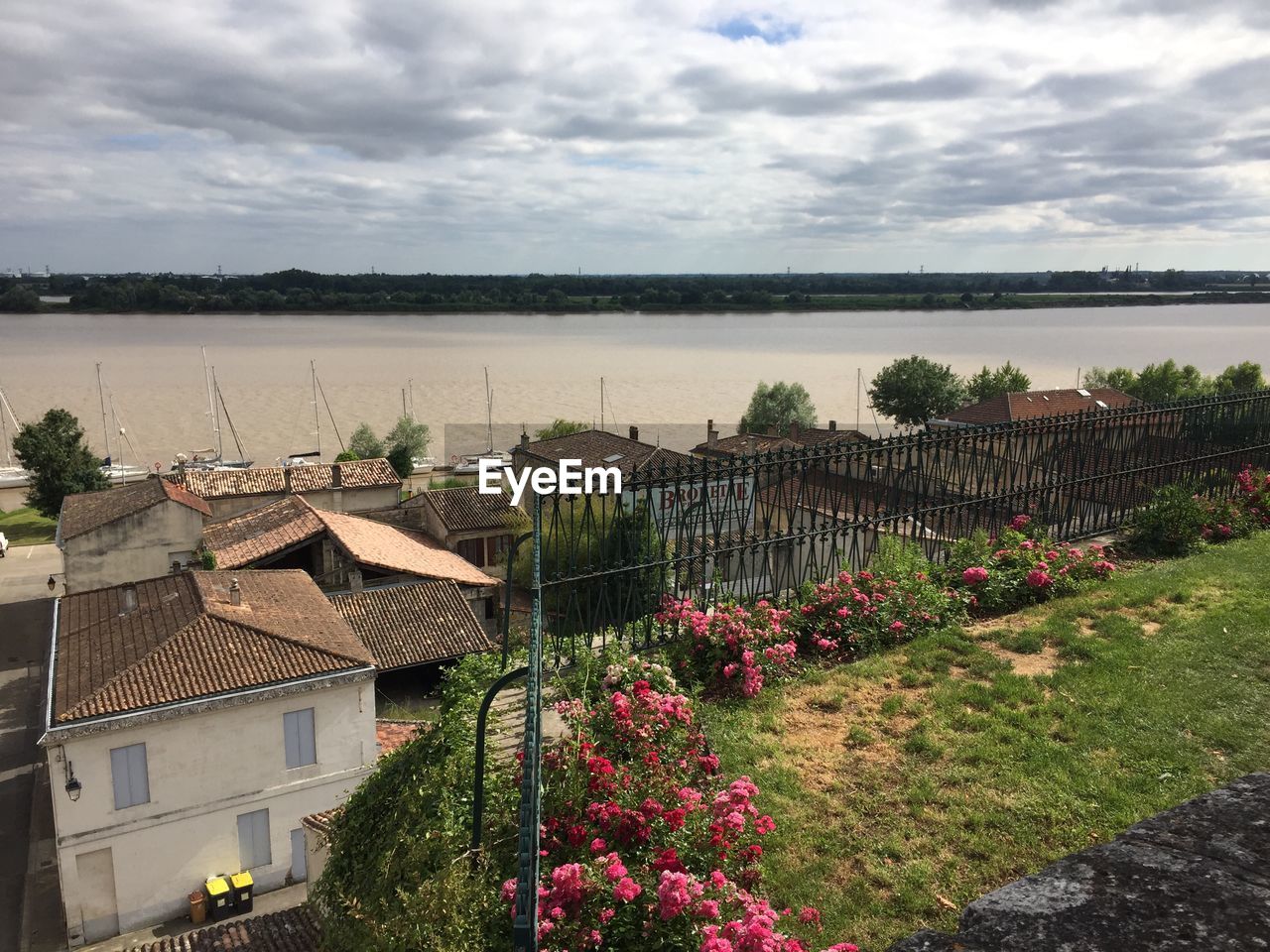 High angle view of houses on field by lake against sky