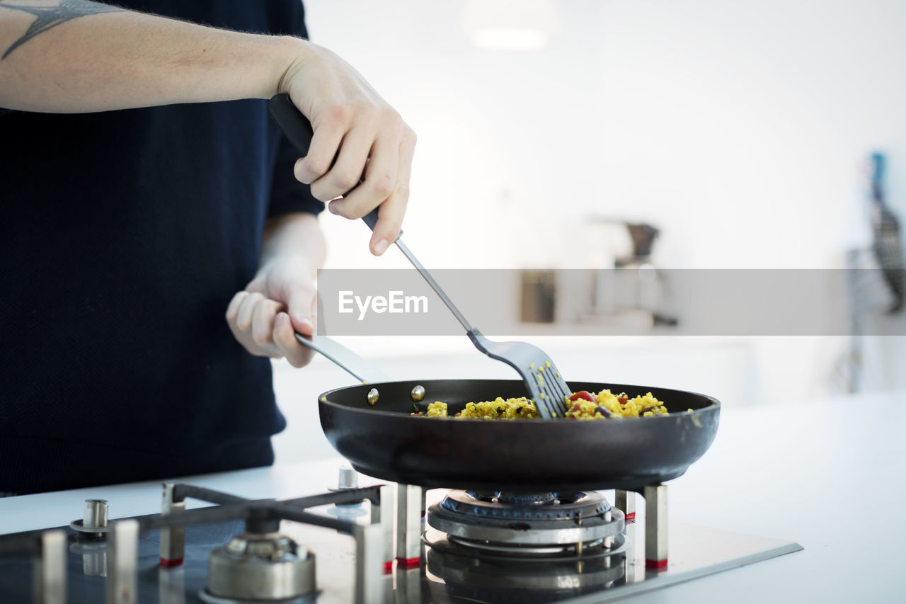 Mid section of man cooking food in kitchen