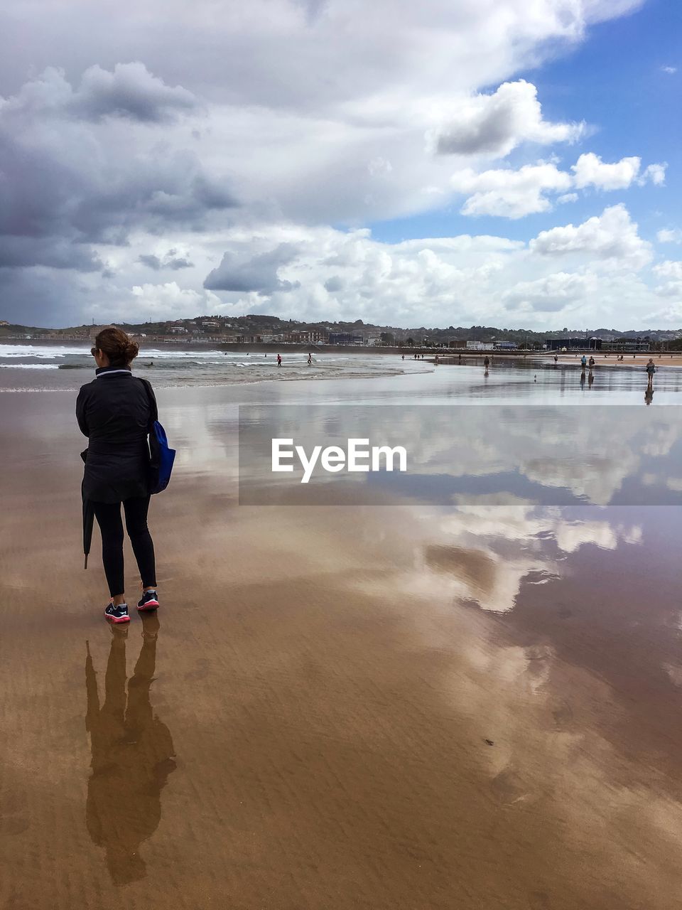 REAR VIEW OF WOMAN STANDING AT BEACH