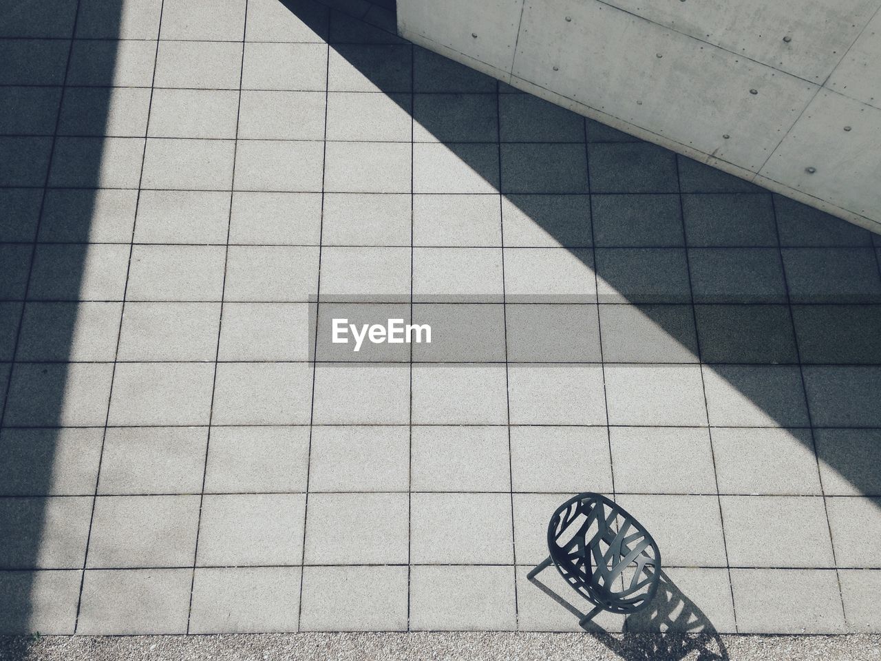 High angle view of empty chair on walkway during sunny day