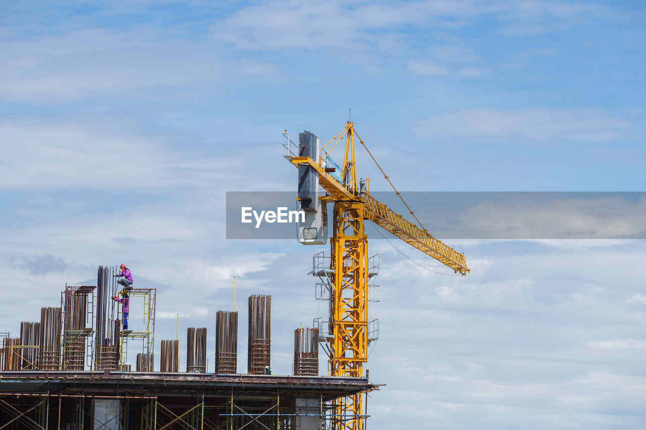 LOW ANGLE VIEW OF CRANE AGAINST BUILDINGS