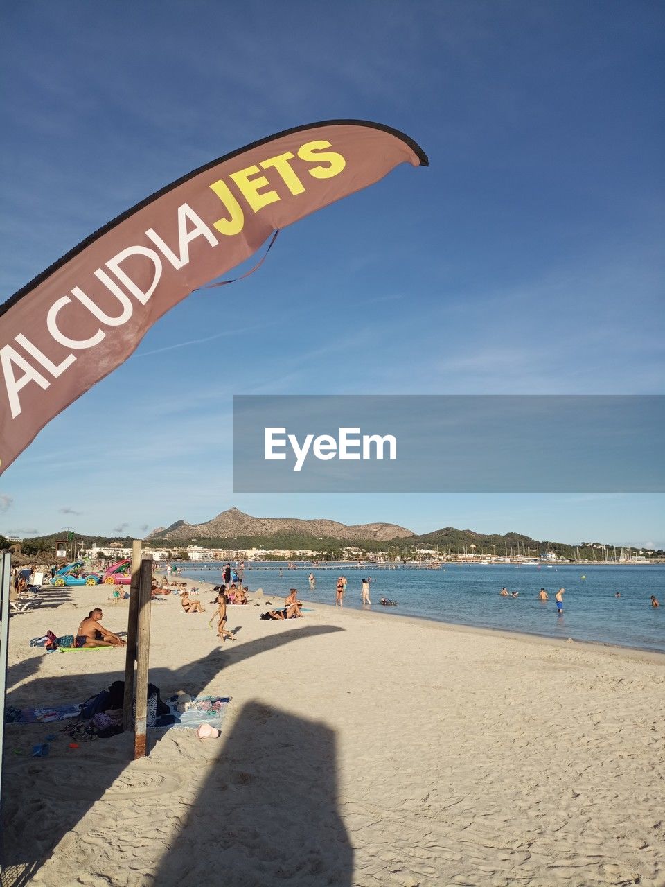 beach, water, land, sea, sky, nature, sand, vacation, trip, holiday, sunlight, day, travel destinations, text, blue, sunny, western script, summer, leisure activity, travel, outdoors, architecture, communication, sign, tourism, coast, scenics - nature, coastline, beauty in nature, clear sky, sports, group of people, city