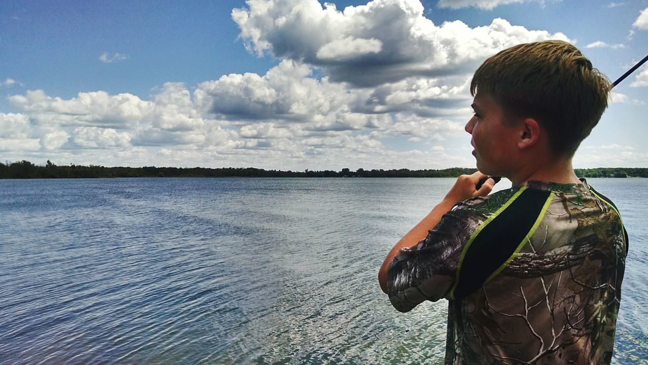 Rear view of boy against lake and sky