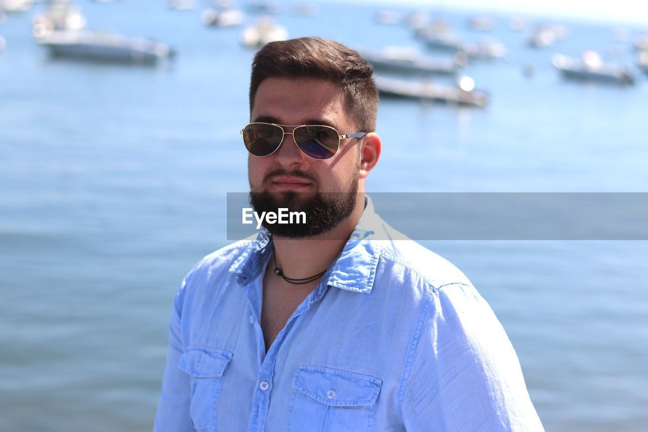 Portrait of smiling young man wearing sunglasses standing at beach
