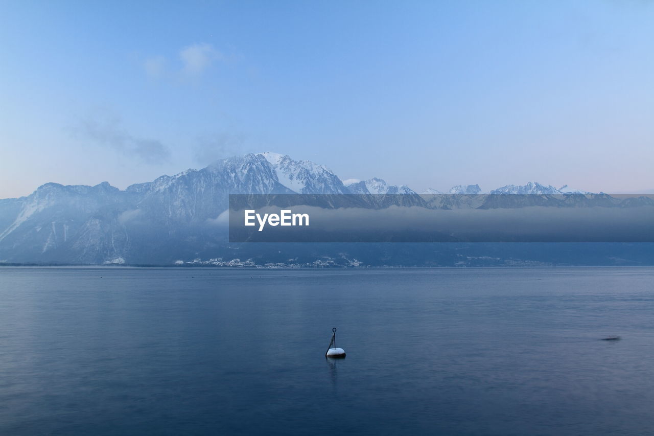 Scenic view of lake geneva and snowcapped mountains against sky