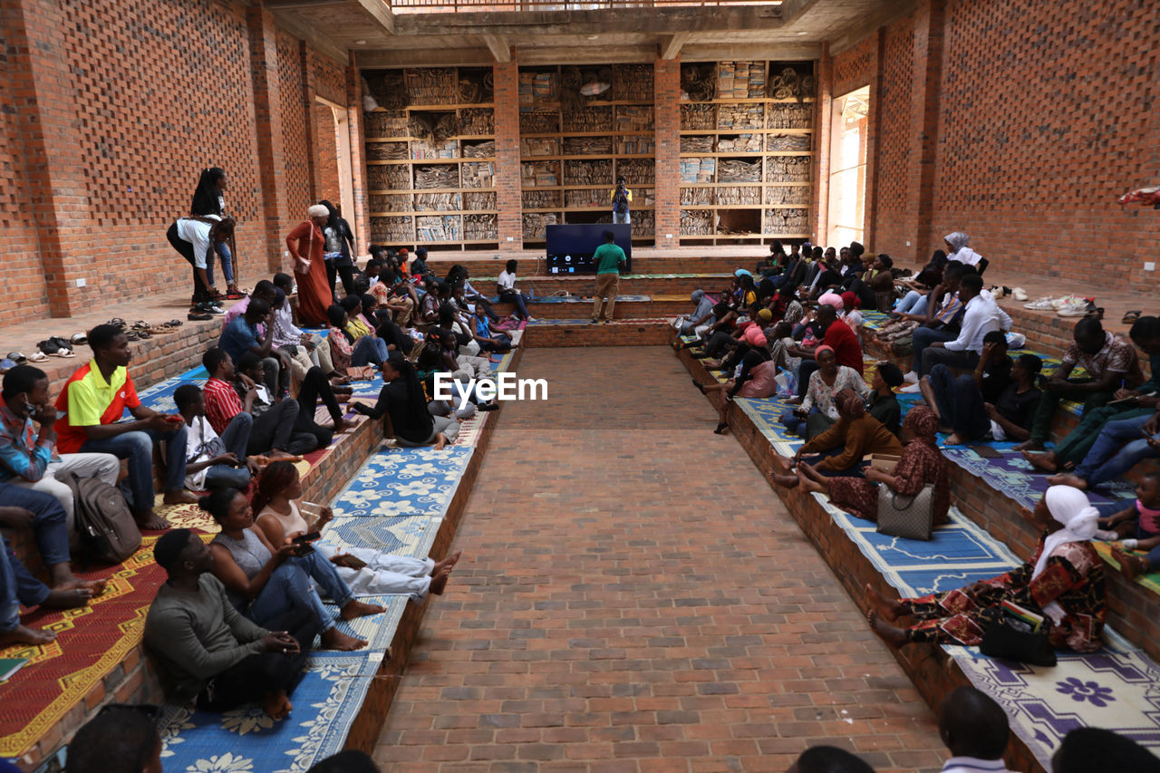 group of people, crowd, large group of people, architecture, men, sitting, women, education, adult, audience, high angle view, person, built structure, indoors, learning