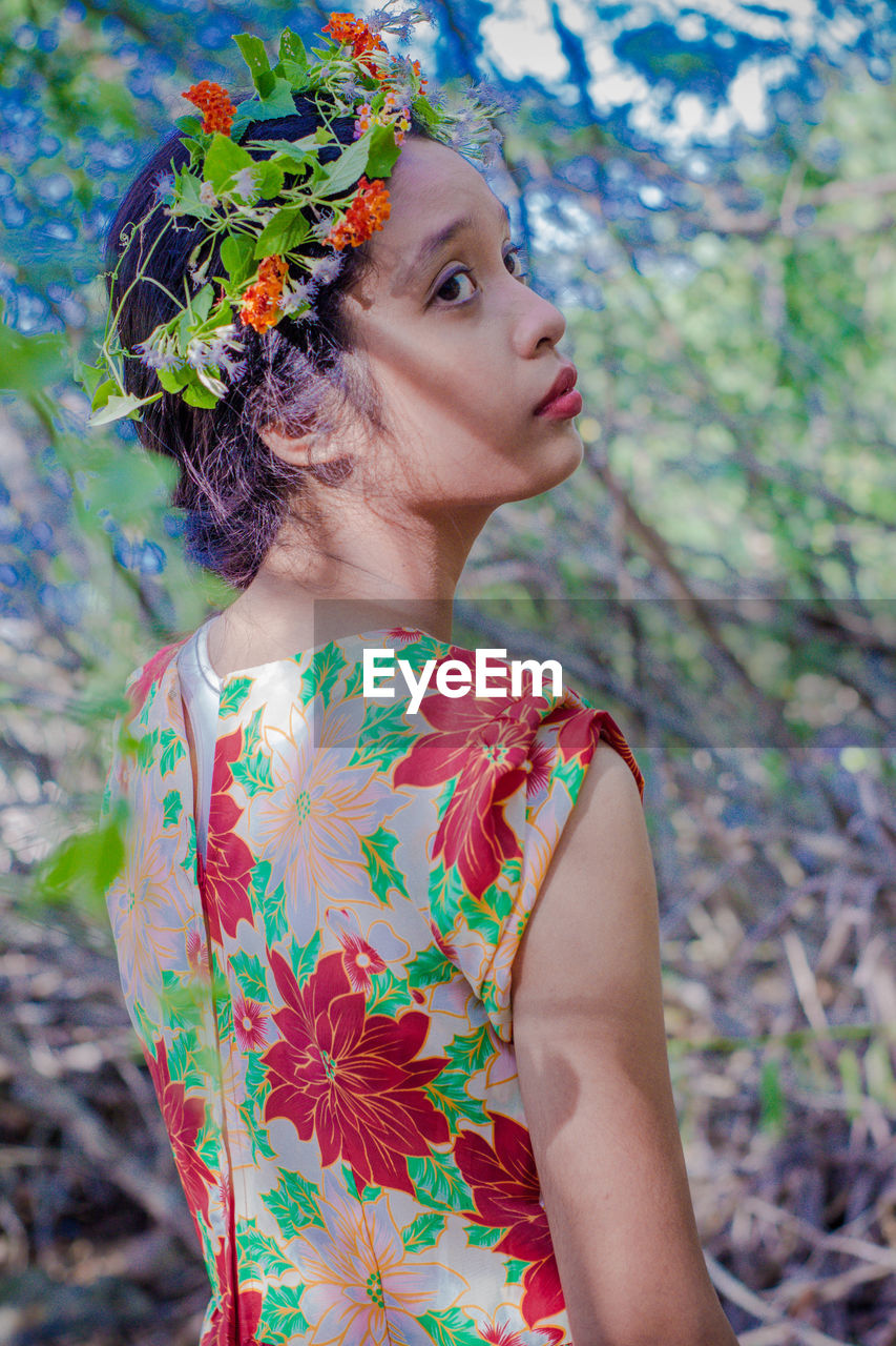 CLOSE-UP OF BEAUTIFUL YOUNG WOMAN STANDING AGAINST TREE