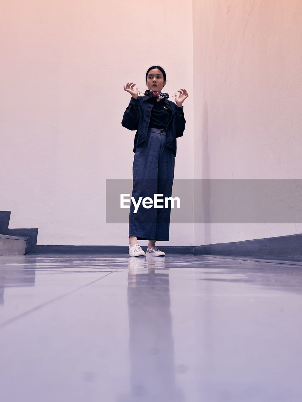 An asian office worker standing at the fire exit area showing off her face mask