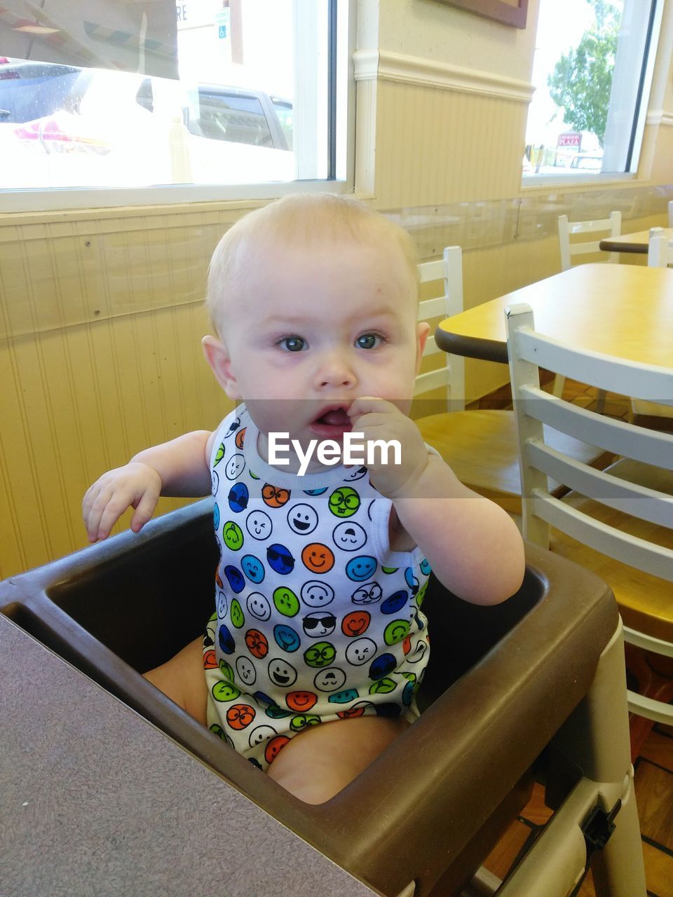 High angle portrait of baby boy sitting on high chair in restaurant