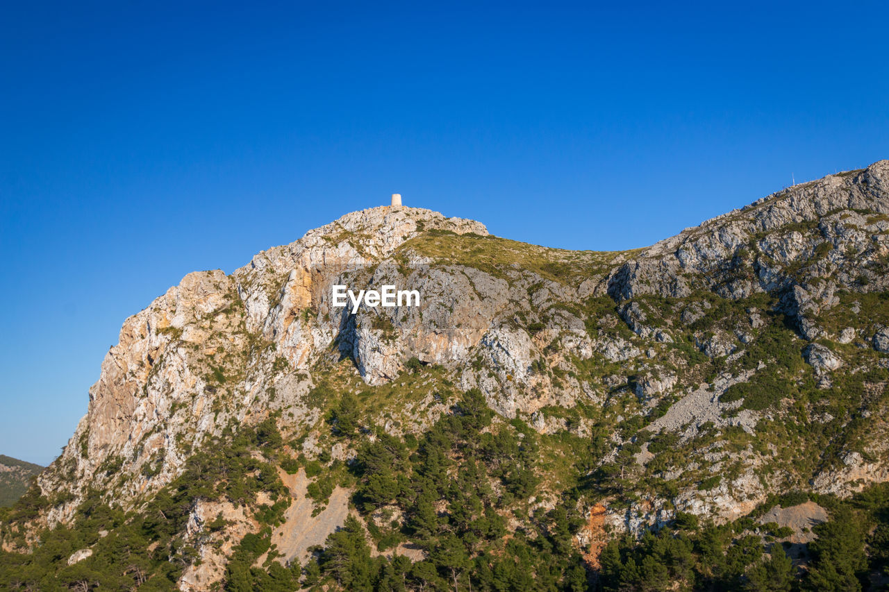 Low angle view of rock formation against clear blue sky