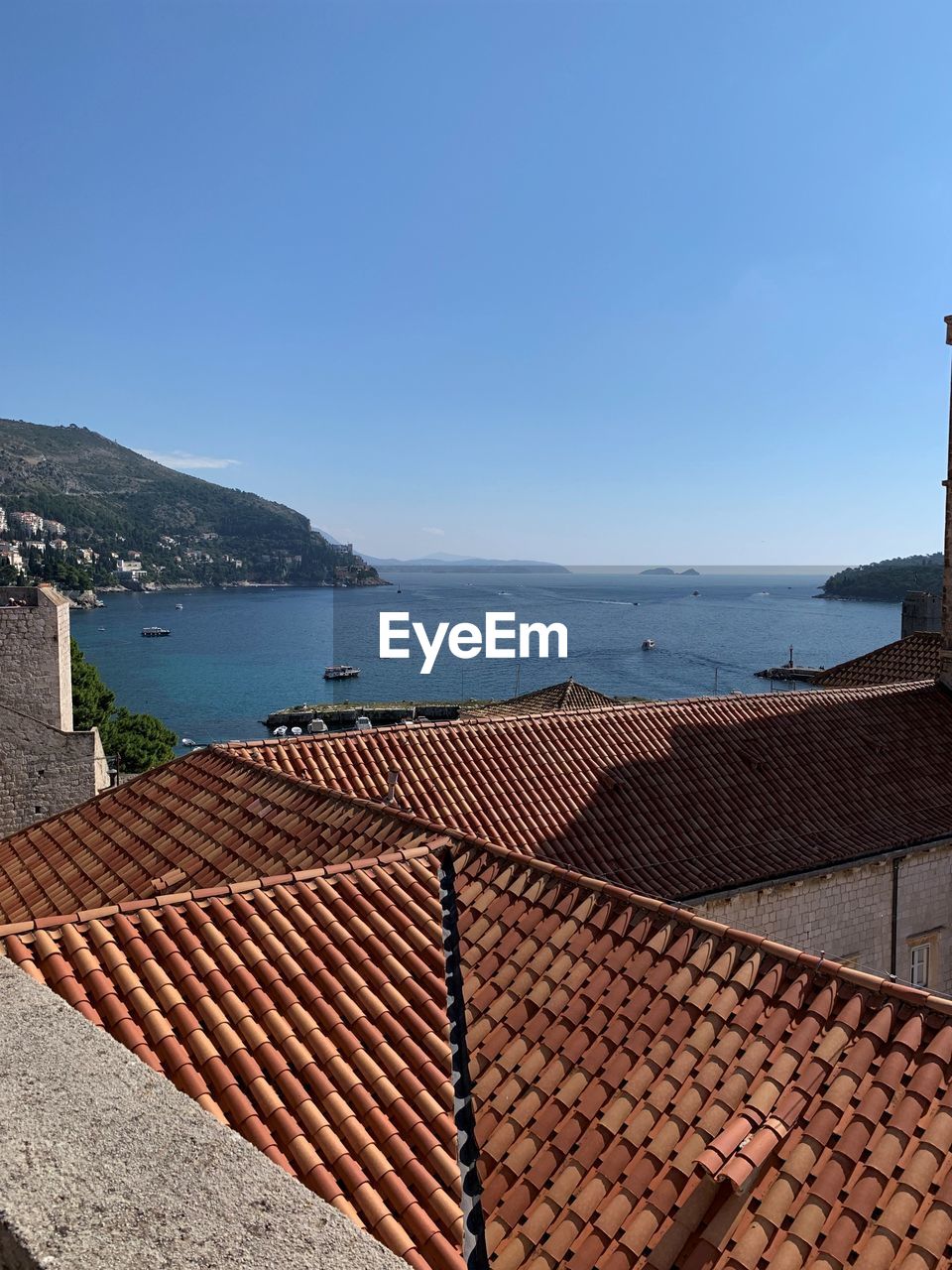 Scenic view of sea by buildings against clear blue sky