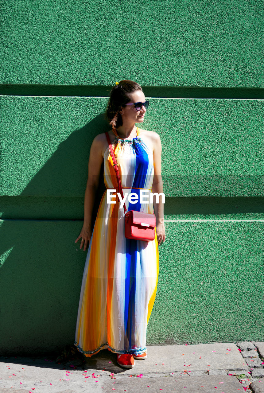 Full length of woman standing against wall outdoors