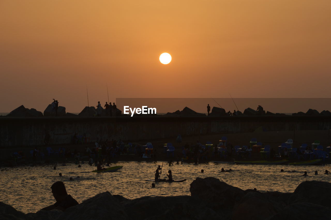 Silhouette of tourists on boats in sea