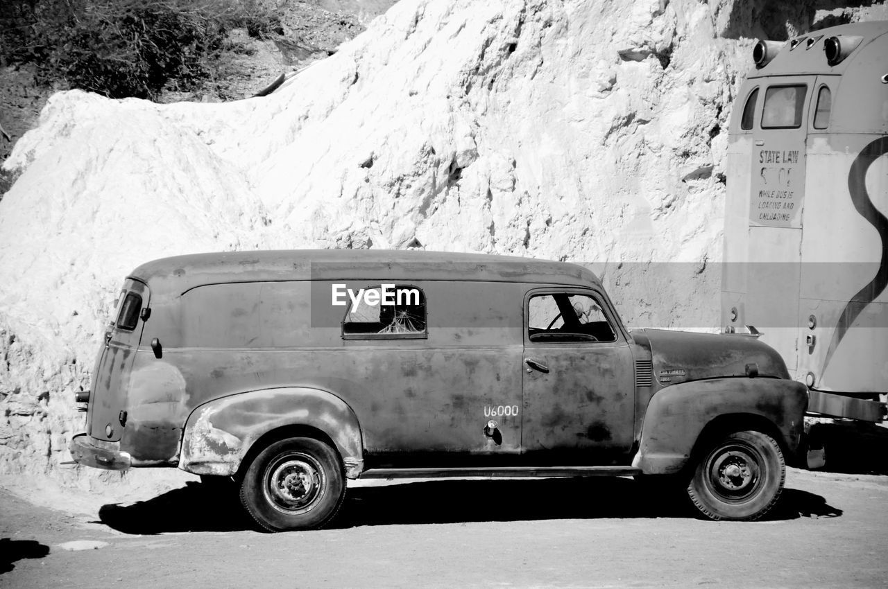 SIDE VIEW OF OLD VINTAGE CAR ON ROAD