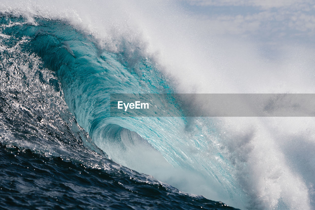 SEA WAVES SPLASHING ON SHORE AGAINST SKY